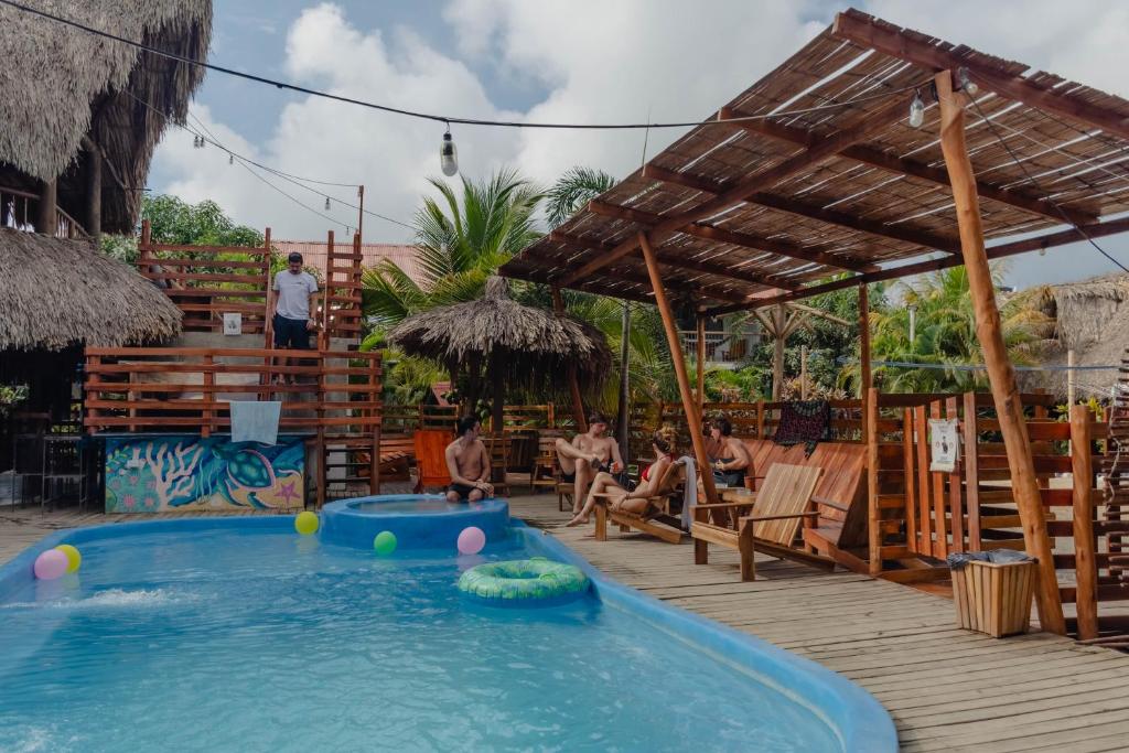 a swimming pool with people sitting on a deck at El Zoo Hostel, Bar & Pool in Palomino