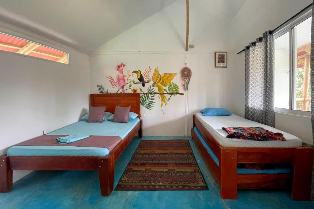 a room with two beds and a window at El Zoo Hostel, Bar & Pool in Palomino
