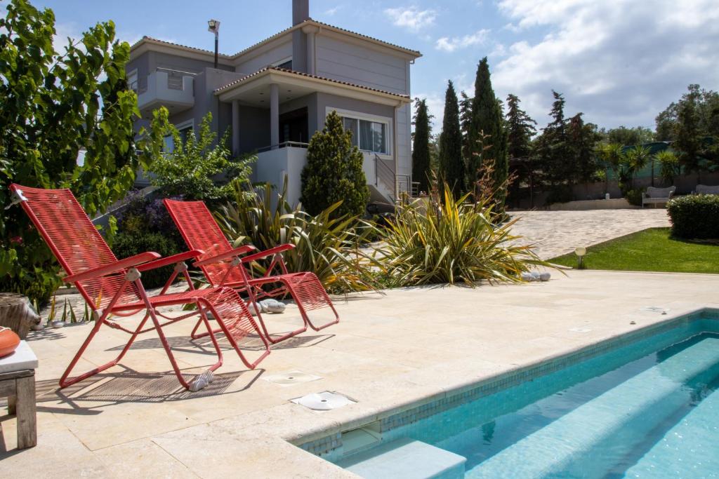 2 sillas rojas sentadas junto a una piscina en Villa Abelos en Loútsa