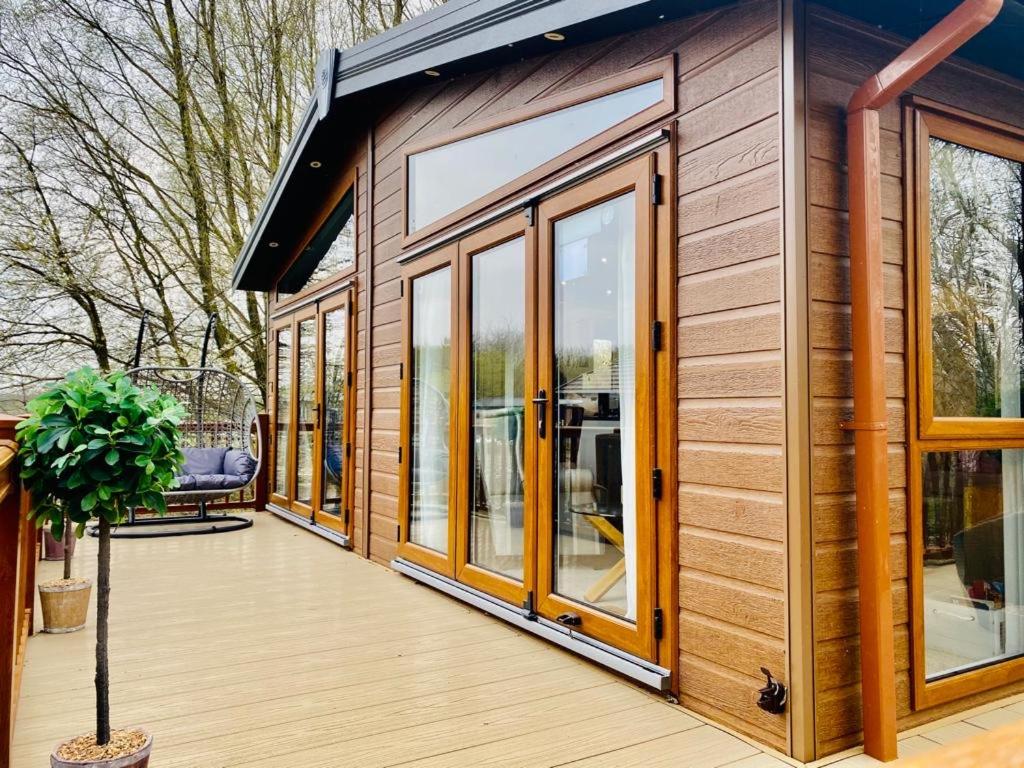 a tiny house with glass doors and a deck at Fairhaven lodge Free Wifi & Hottub in Warton