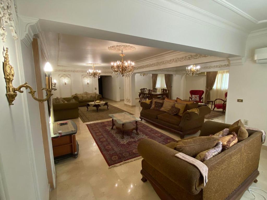 una gran sala de estar con sofás y una mesa. en Luxurious, fully furnished and well-equipped apartment with modern amenities, stunning views, and convenient location for remote work or studying from home, en El Cairo