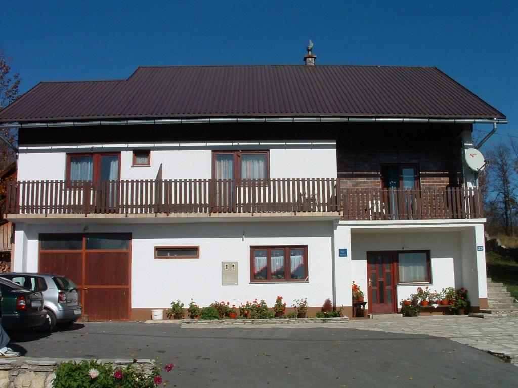 a white house with a balcony on top of it at Guest House Tone in Poljanak