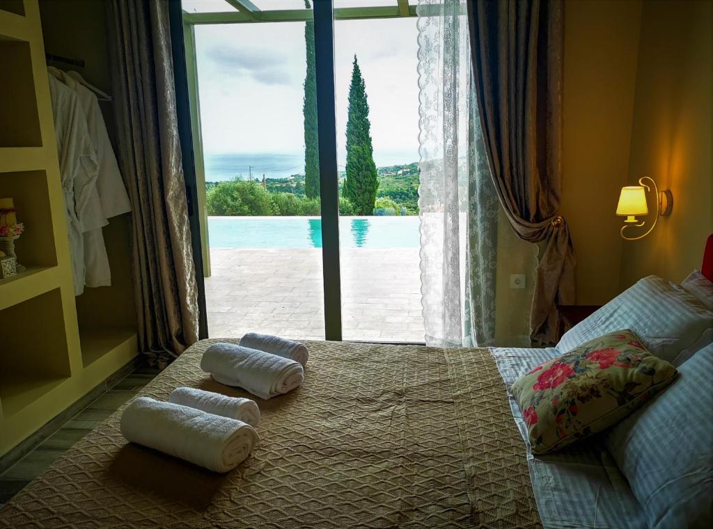 1 dormitorio con toallas en una cama con ventana en ReLux Villa en Kefallonia