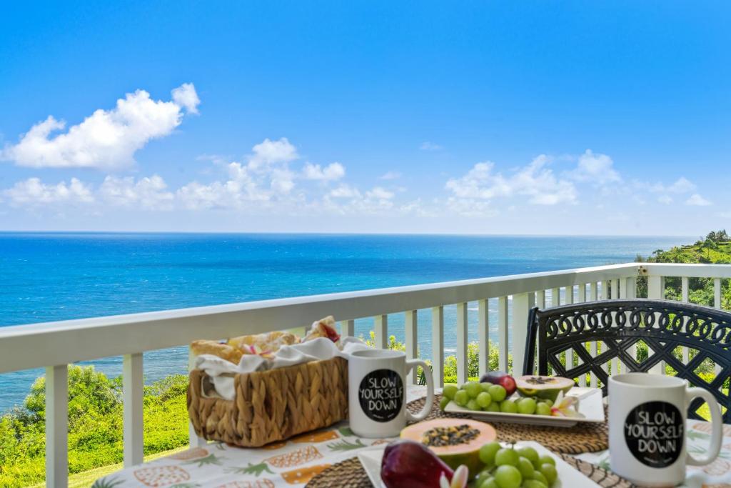 una mesa con comida en un balcón con vistas al océano en Breathtaking Ocean View of Royal Waters! AK5202, en Princeville