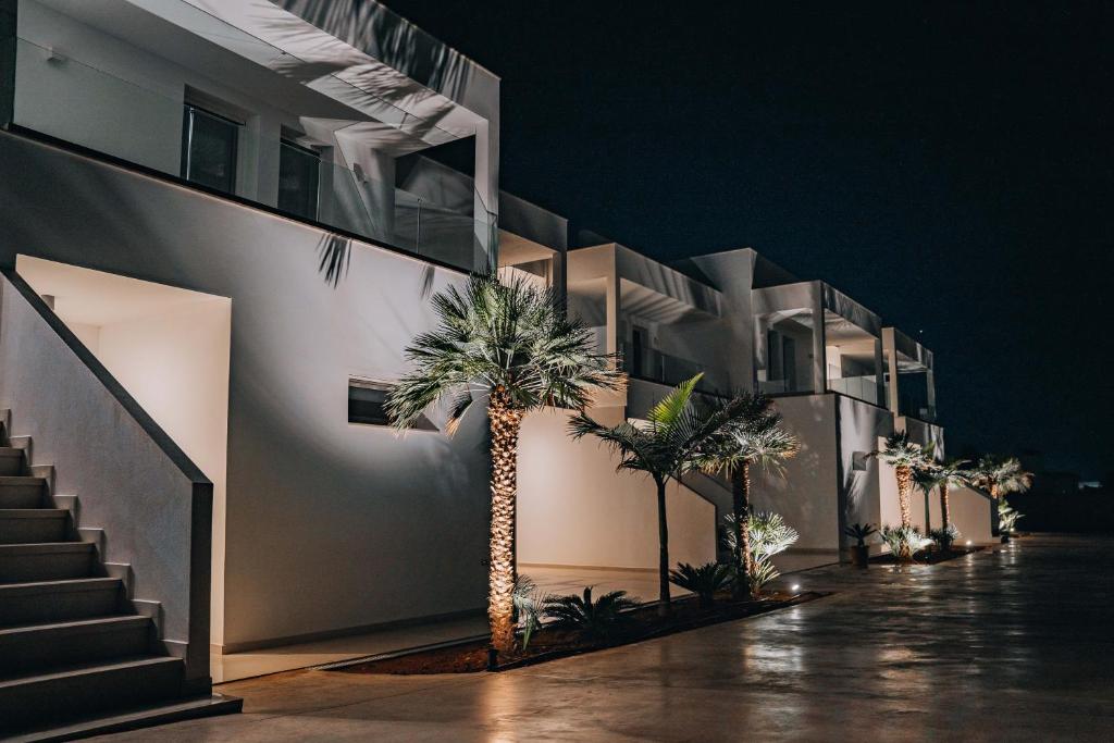 een gebouw met palmbomen en 's nachts trappen bij Grand White Apartments in Agios Ioannis