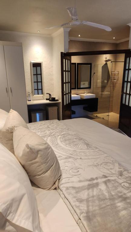 a bedroom with a large white bed and a bathroom at Rest&Relax Guesthouse in Johannesburg