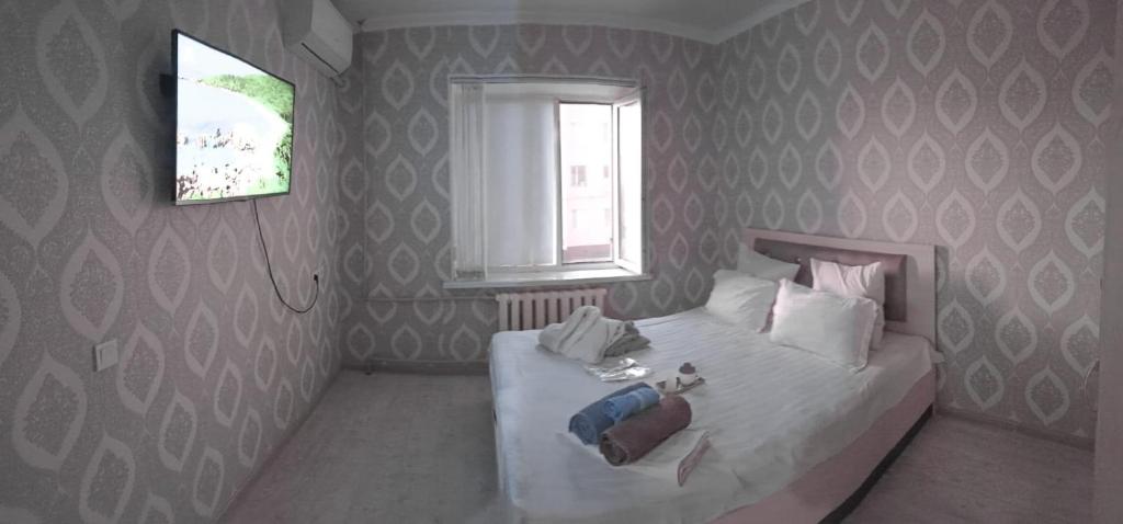 a bedroom with a white bed with a window and a window at 2 комнатная в микрорайоне Шугыла in Qyzylorda