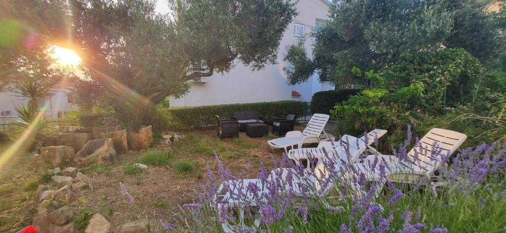 ラブにあるPadova 2の白い椅子と紫の花が咲く庭園
