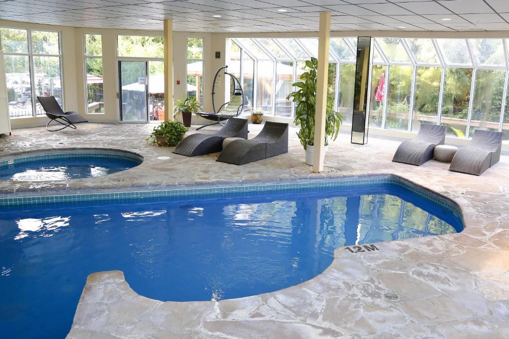 a swimming pool in a house with chairs at Excelsior Hôtel Spa Sainte-Adèle in Sainte-Adèle