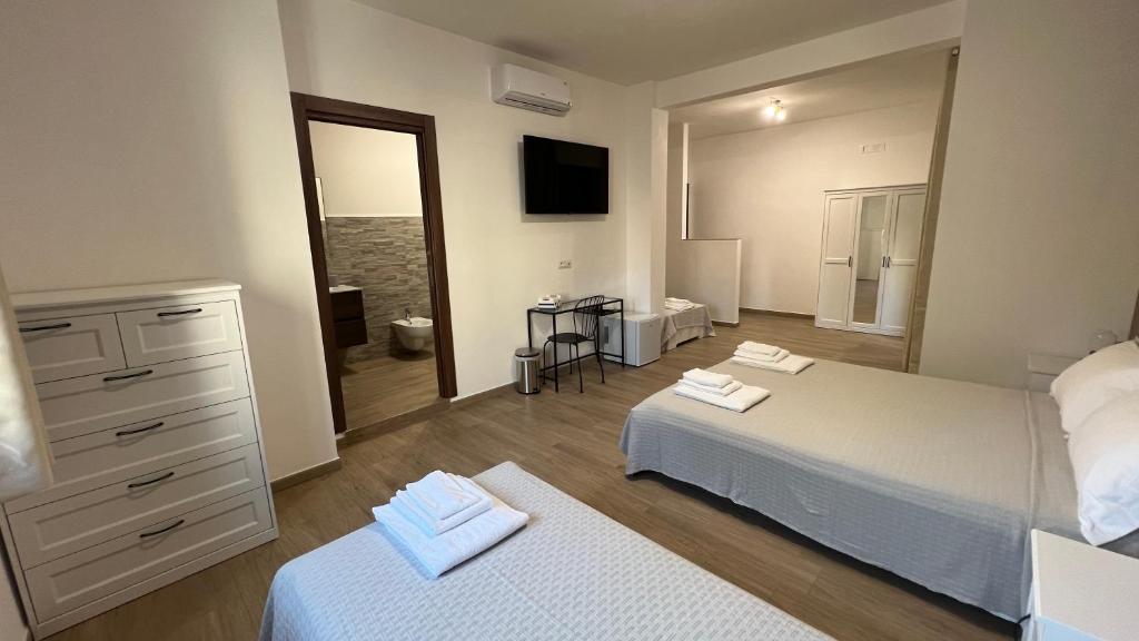 a bedroom with two beds and a dresser and a mirror at Cala Portavecchia in Monopoli
