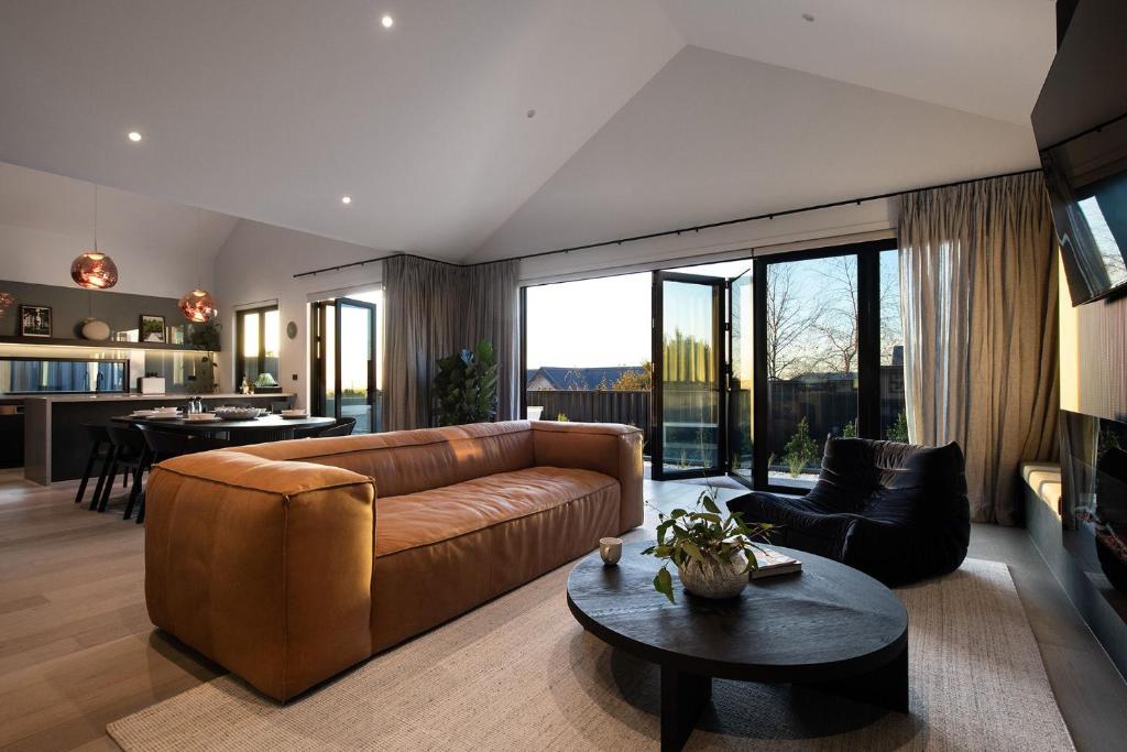 a living room with a brown couch and a table at Scandi Haus- seamless design, modern luxury in Daylesford