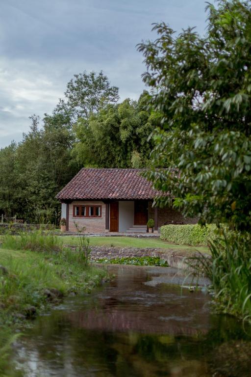 a small house with a pond in front of it at El Molino de Bonaco in San Vicente de la Barquera