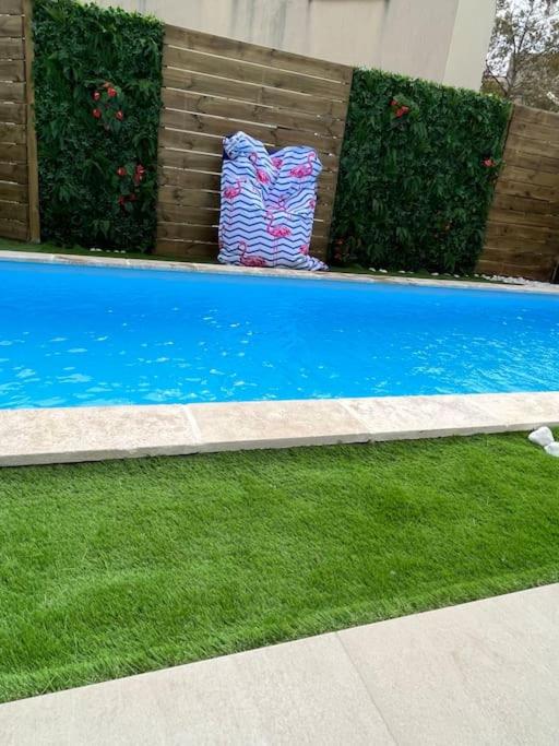 une piscine bleue avec de l'herbe verte et des buissons dans l'établissement Villa La caroline 2, à Montpellier