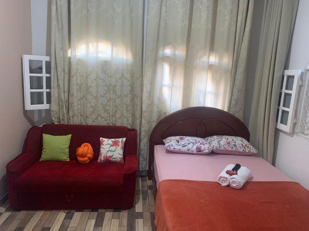 um quarto com 2 camas e uma cadeira vermelha em Apto Amar - No Espaço Florescer em Campos dos Goytacazes