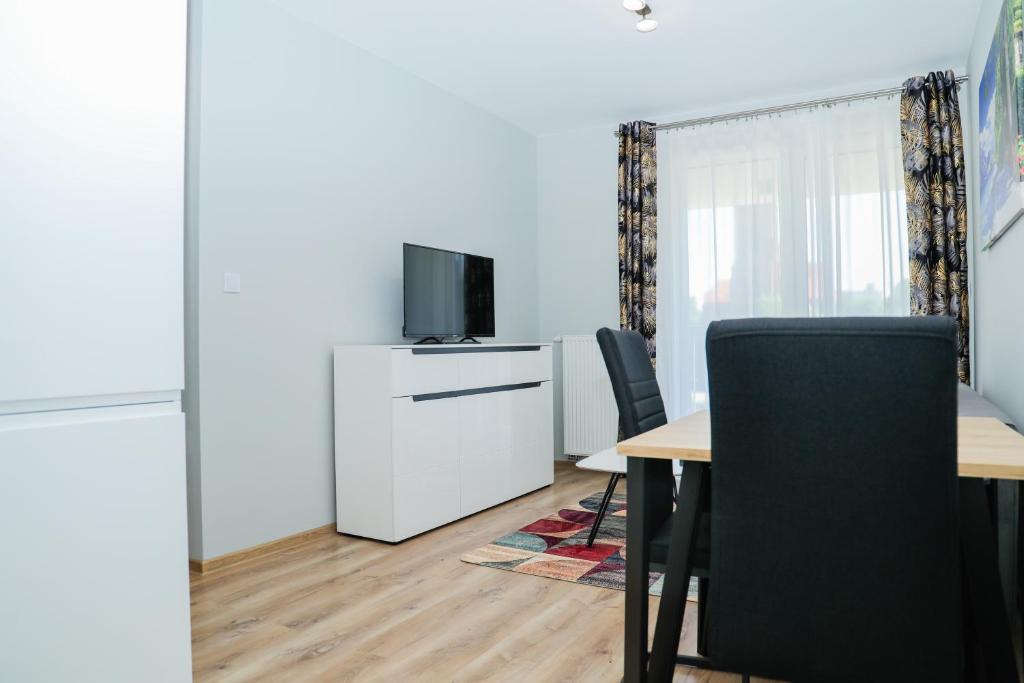ein Esszimmer mit einem Tisch und einem TV in der Unterkunft Modern Apartments in center of Katowice in Kattowitz