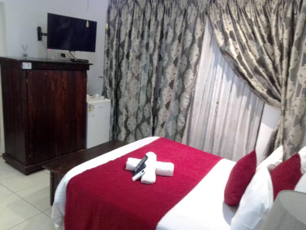 een slaapkamer met een rood en wit bed en 2 handdoeken bij Umqhele BnB in Richards Bay