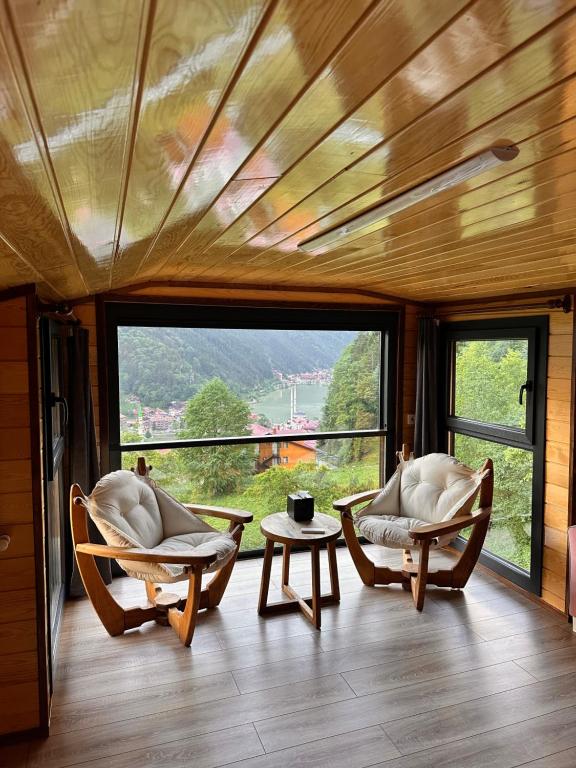 ウズンギョルにあるÖzen Villa Apartの大きな窓のある客室で、椅子2脚とテーブル1台が備わります。