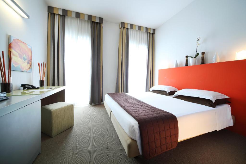 a hotel room with a bed with a red wall at Hotel Trieste in Rimini