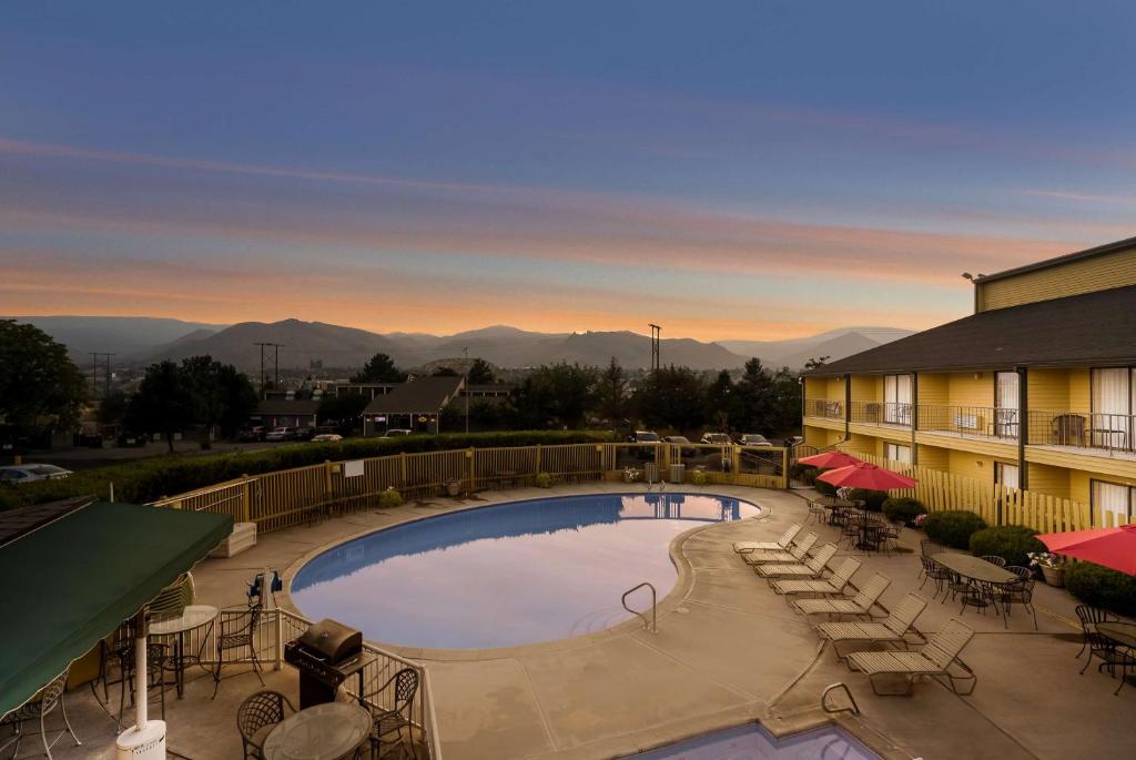 a resort with a pool and mountains in the background at SureStay Hotel by Best Western Wenatchee in Wenatchee