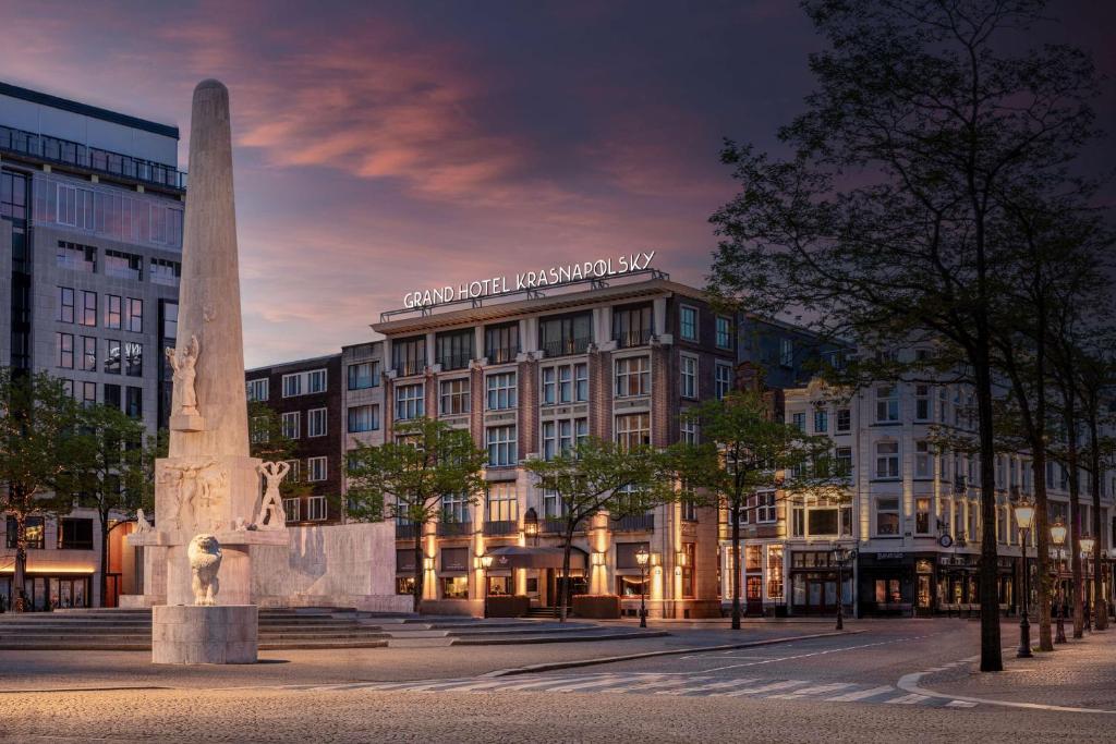 un edificio con un monumento di fronte ad esso di Anantara Grand Hotel Krasnapolsky Amsterdam ad Amsterdam