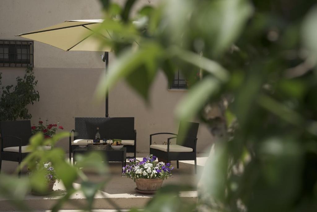 un patio con sillas, sombrilla y flores en Casa delle Macine, en Caltanissetta