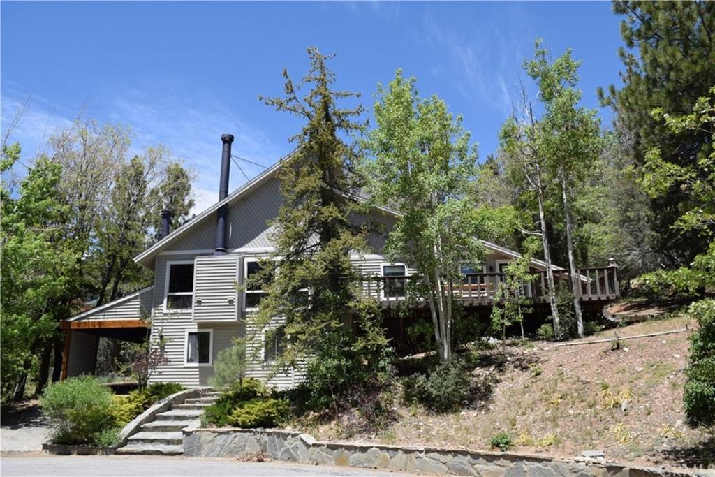 a white house with a porch and trees at Cozy Bear Chateau -Beautiful Moonridge home nestled in the pines and birches in Big Bear Lake