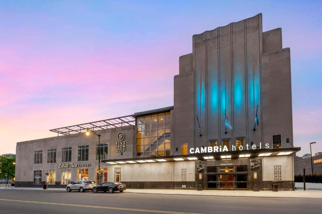 Cambria Hotel Detroit Downtown في ديترويت: مبنى كبير فيه سيارات تقف امامه