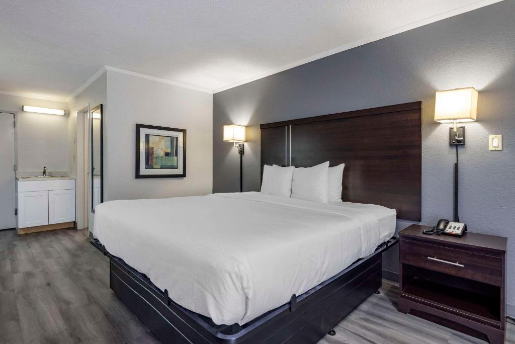 a hotel room with a large bed and a bathroom at Suburban Studios in Rock Hill