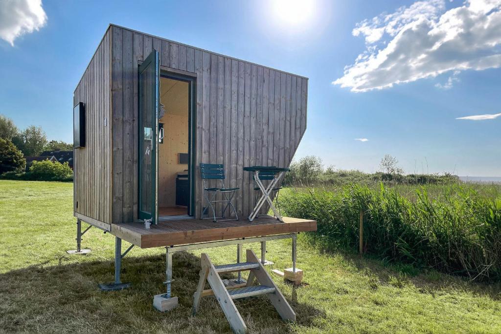 Une petite maison sur un stand dans un champ dans l'établissement Sleep Space 4 - Green Tiny Spot Cuxhaven Altenbruch, à Cuxhaven