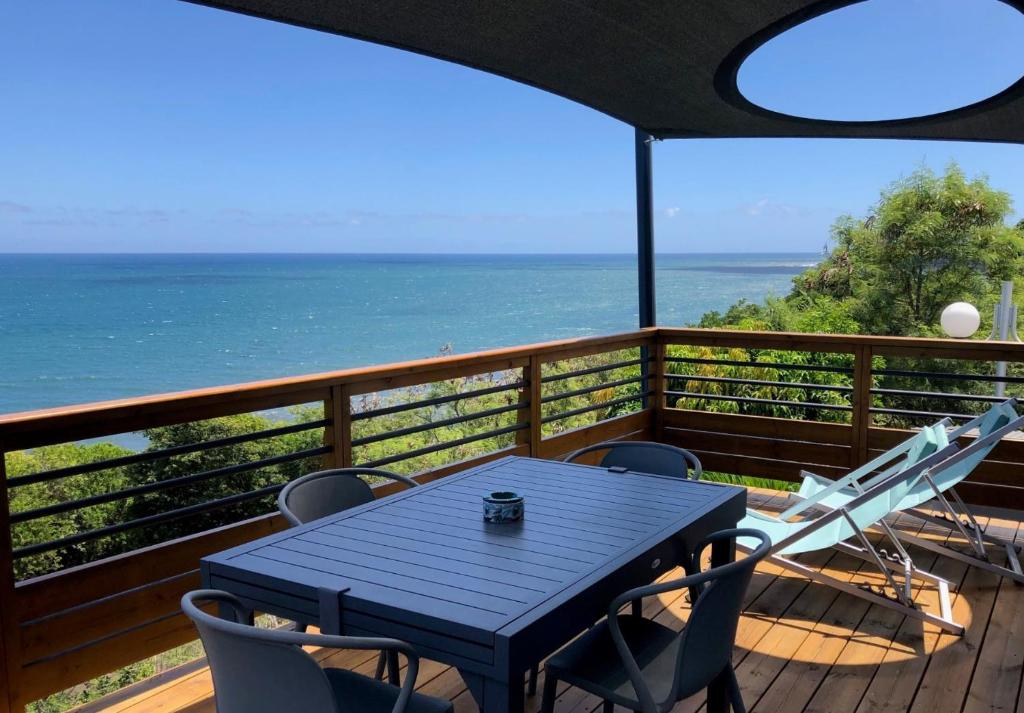 - une table et des chaises sur une terrasse avec vue sur l'océan dans l'établissement Les Pailles en Queue - Appartements de Charme & Standing, à Sainte-Marie