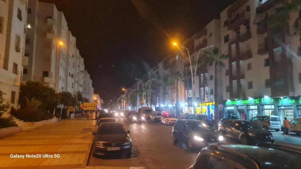 een drukke stadsstraat 's nachts met auto's geparkeerd bij salamappart in Agadir