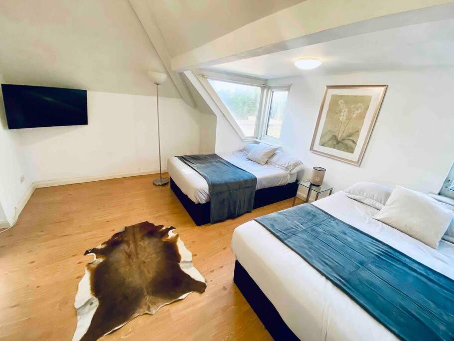 a bedroom with two beds and a tree stump on the floor at Penthouse studio with 2 double beds & smart TV. Great London Location in London