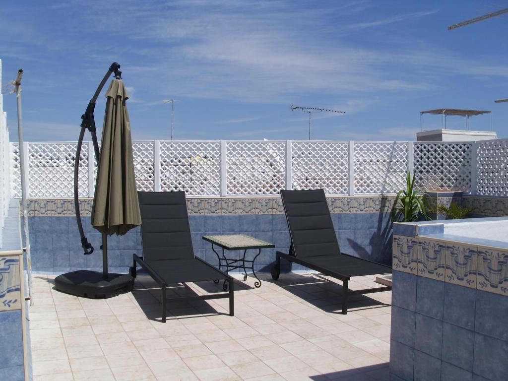 a patio with two chairs and an umbrella and a table at Casa Marina Olhao in Olhão