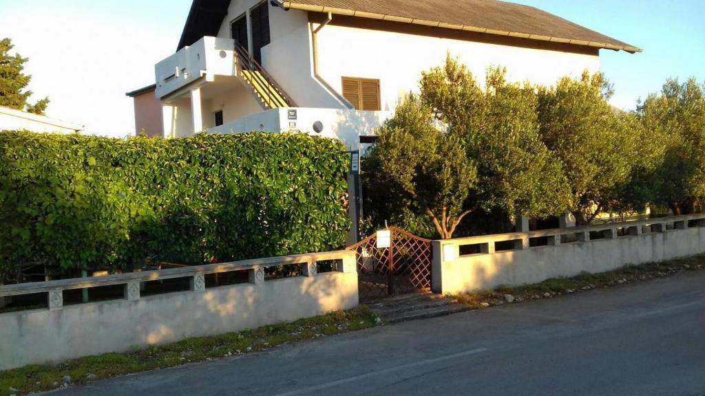 une maison avec une clôture en face d'une rue dans l'établissement Apartments and rooms by the sea Pirovac, Sibenik - 21487, à Pirovac