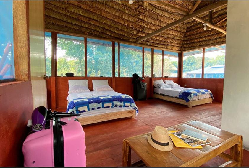 Cette chambre comprend deux lits et une table avec une valise. dans l'établissement Ceiba Amazon Lodge, à Iquitos