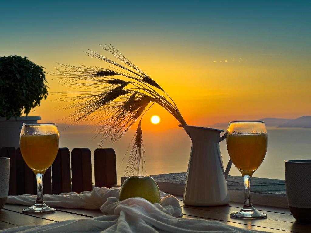 a table with two glasses of wine and a sunset at Aegean Balcony Studio in Áno Meriá