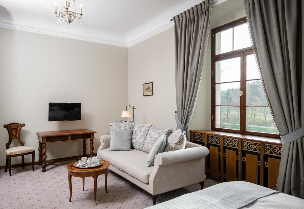 Quiet sitting area with pale sofa, small round table, wooden desk and window view