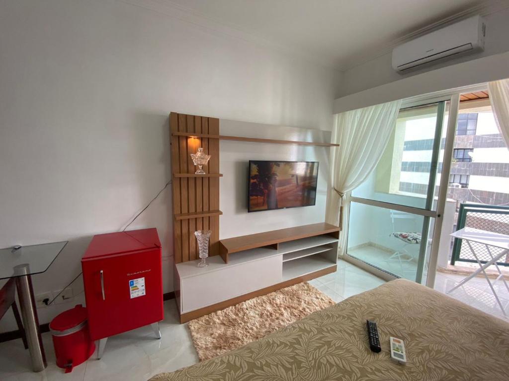 a living room with a flat screen tv and a red cabinet at Flat Beira Mar Piedade in Recife