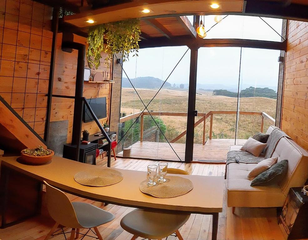 a living room with a table and a large window at Cabana Cambará in Cambara do Sul