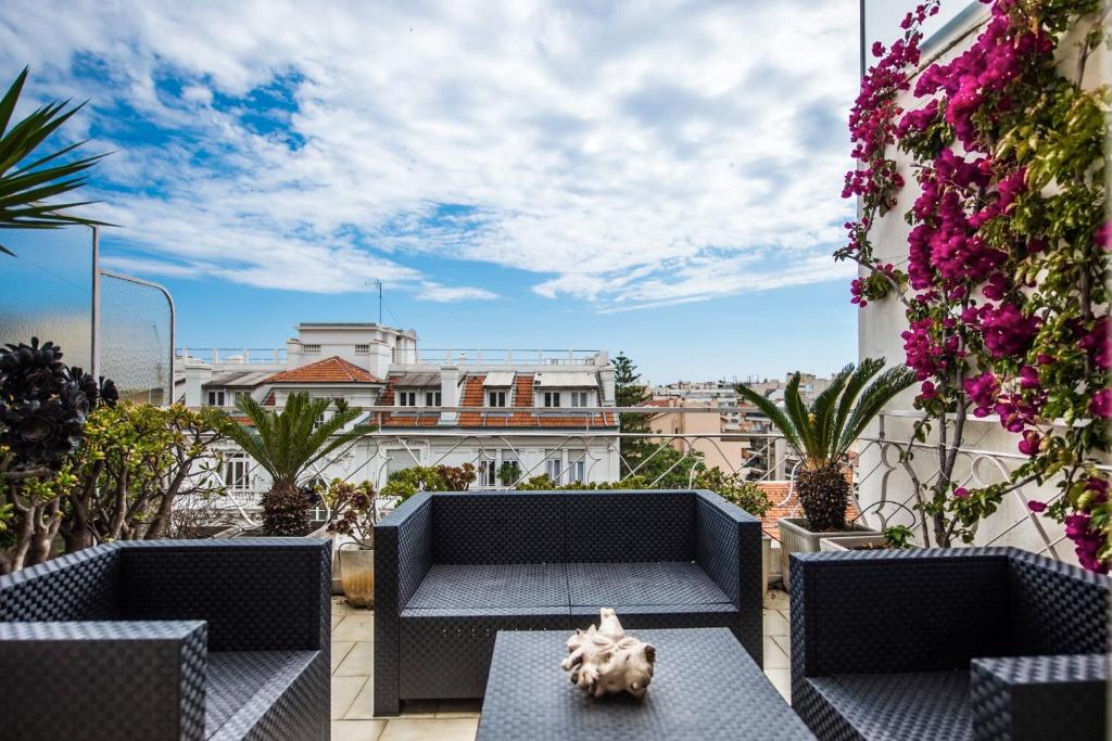 un patio con sillas, una mesa y flores en Fleurs de Nice furnished flat en Niza