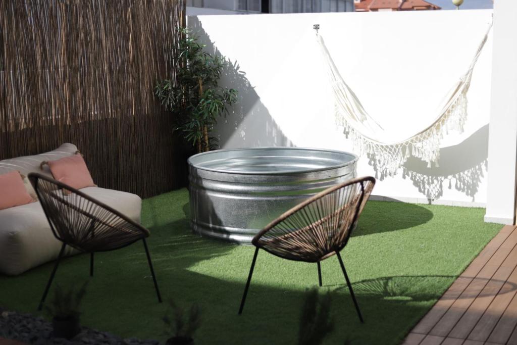 a patio with two chairs and a large bucket at Peniche Supertubos Terrace in Peniche
