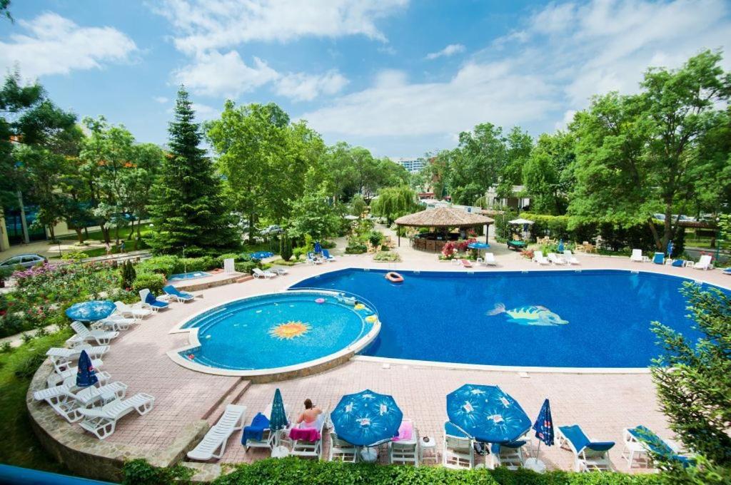 una piscina en un complejo con sillas y sombrillas en Regina Hotel, en Sunny Beach