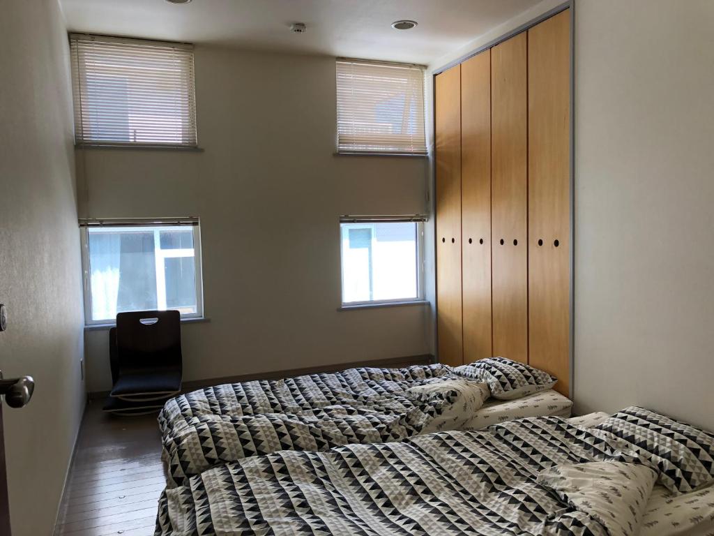 釧路市にあるart.paradigmのベッドルーム1室(ベッド2台、椅子、窓付)