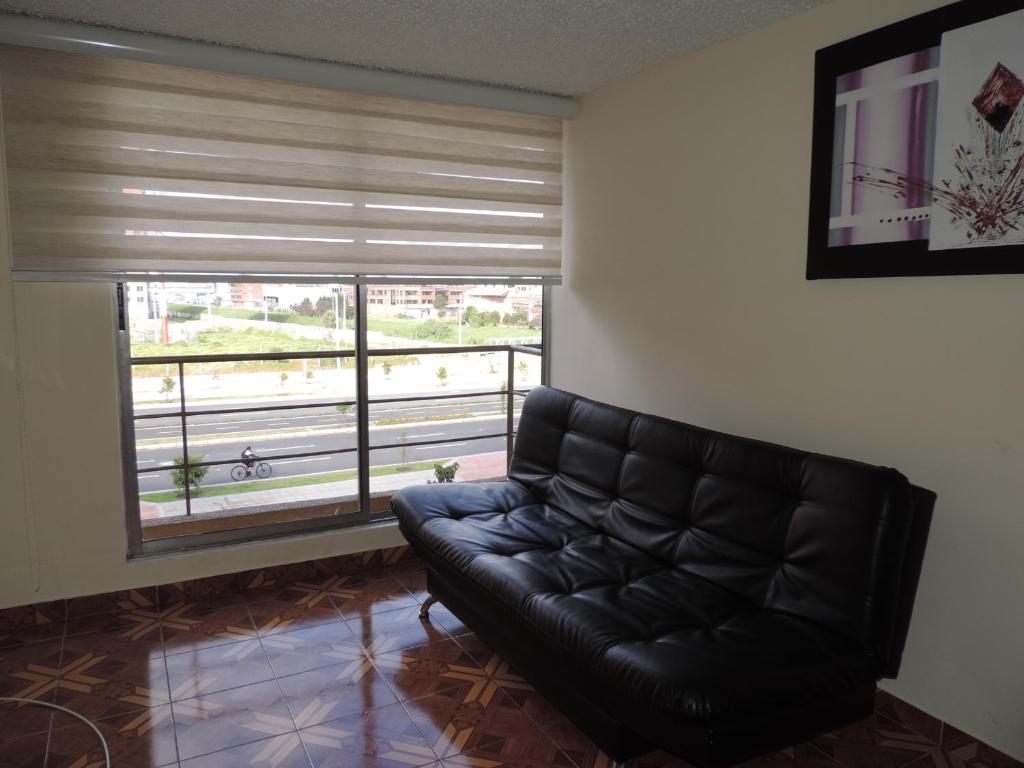 un sofá de cuero negro en una sala de estar con ventana en LO MEJOR DE BOGOTAa, en Bogotá
