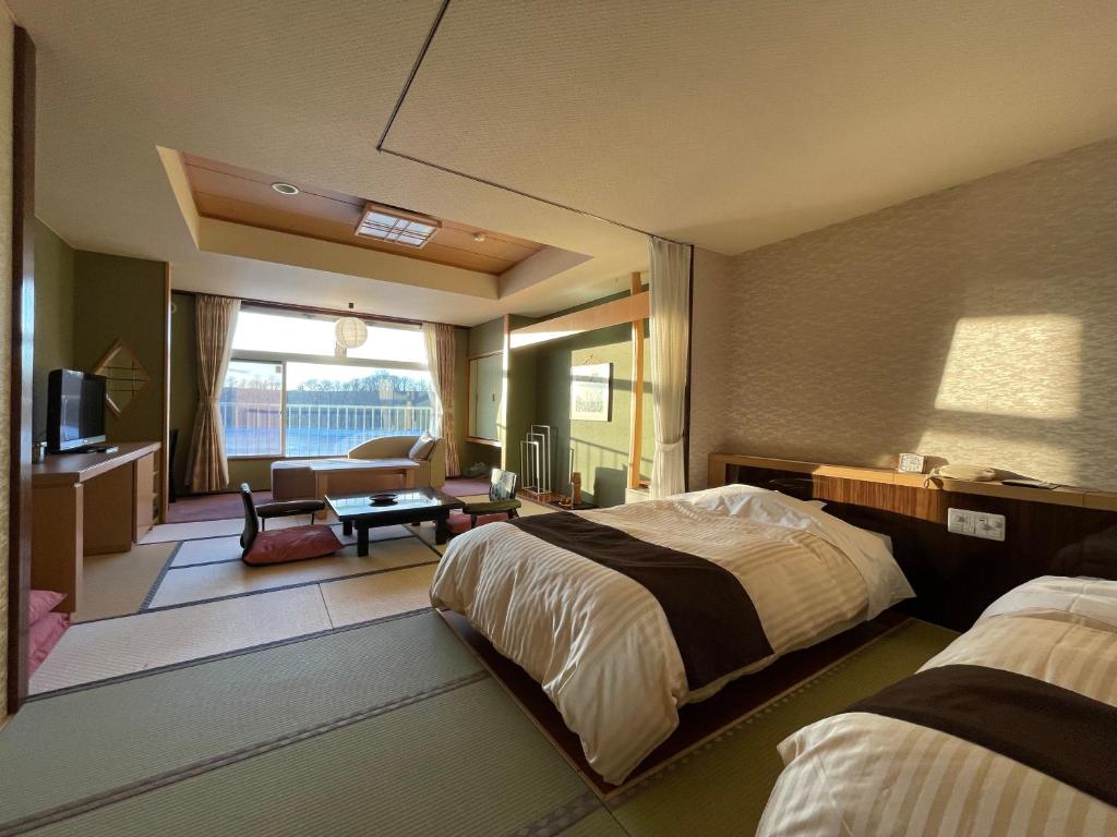 a hotel room with two beds and a living room at Hotel Abashirikoso in Abashiri