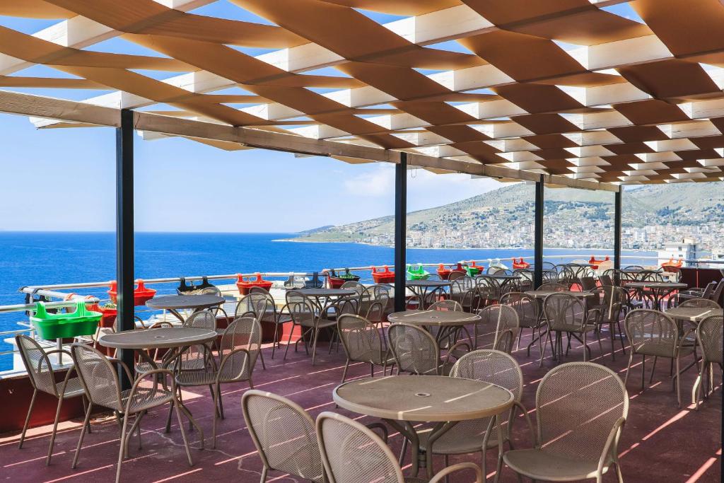a patio with tables and chairs and the ocean at Summer Dream Hotel in Sarandë