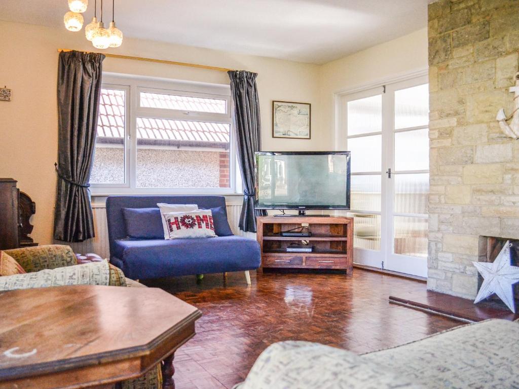 sala de estar con sofá azul y TV en Botany Bay Bungalow, en Kingsgate