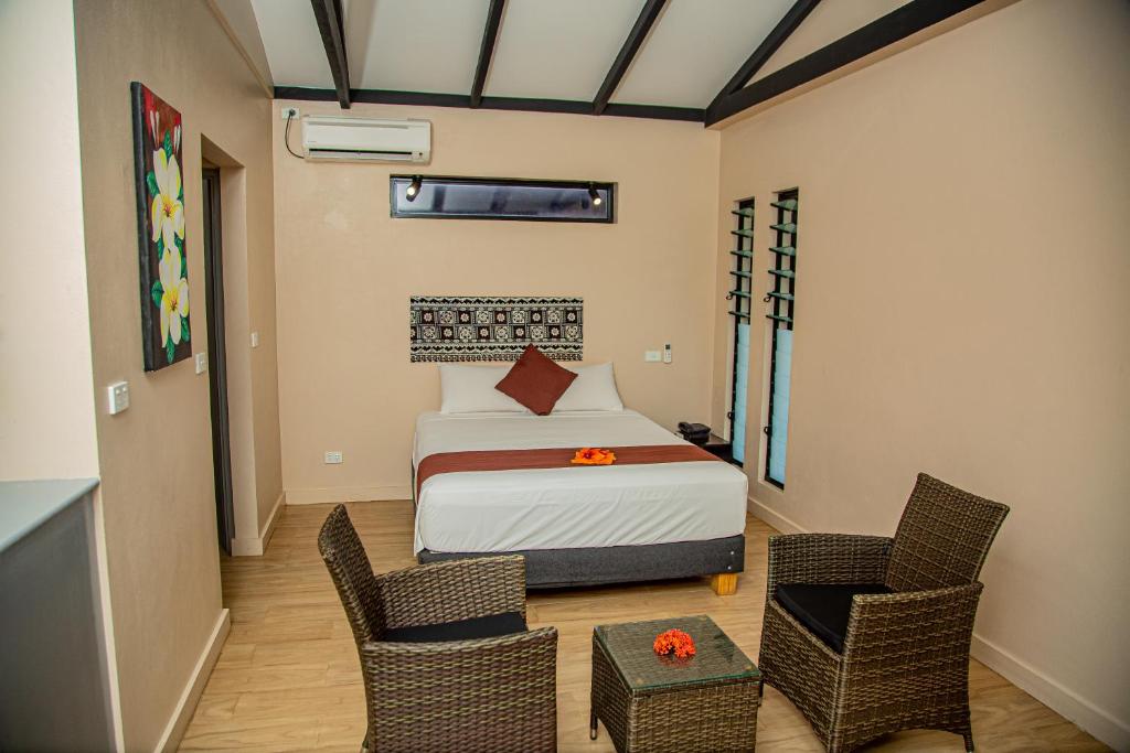SigatokaSeatiki Resort Fiji的一间卧室，里面有一张床和两把椅子