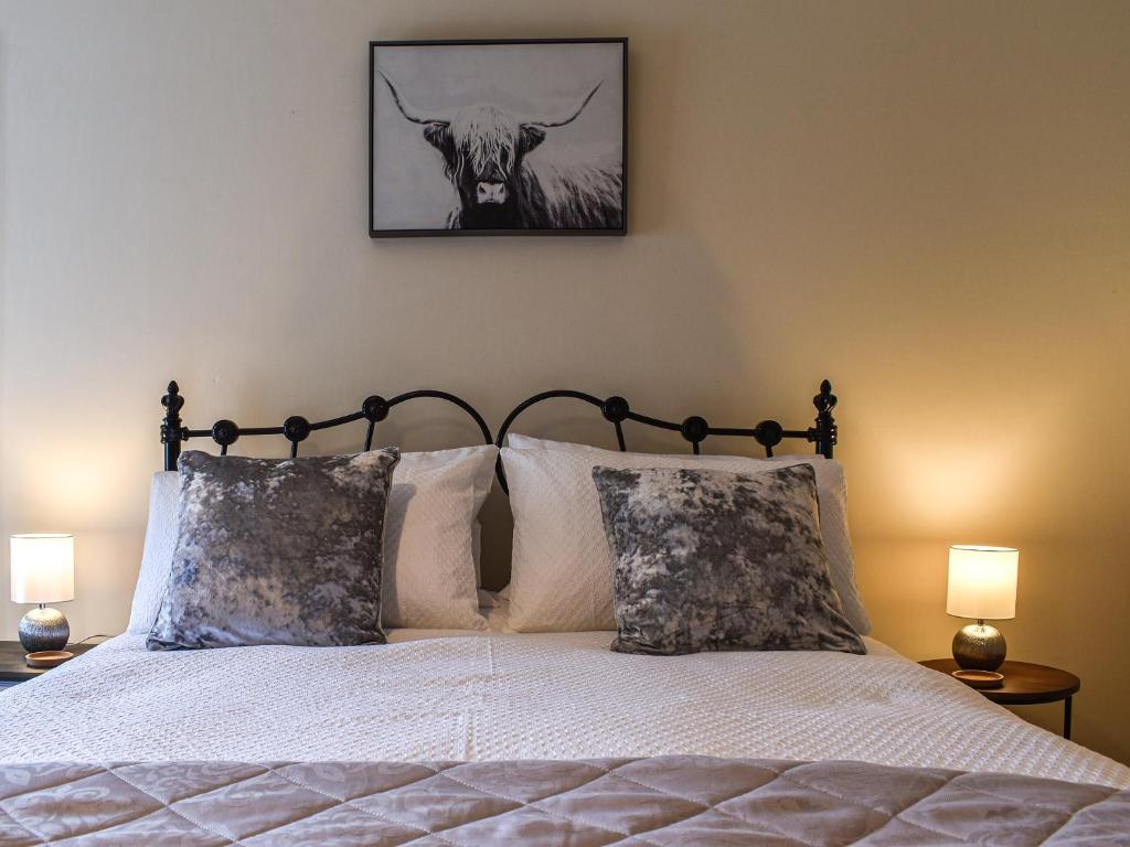 a bed with two pillows and a picture of a bull at Low View in Chelmorton