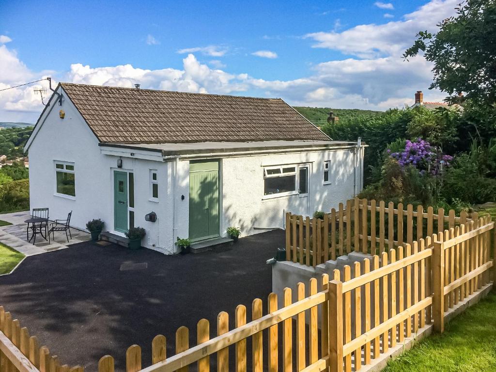 una pequeña casa blanca con una valla de madera en Ty Howton, en Clydach